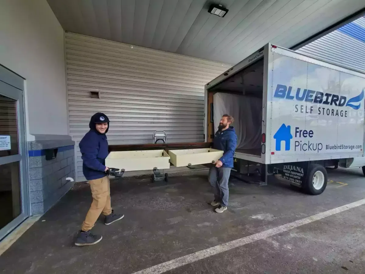 Two Bluebird Self Storage employees carrying furniture.