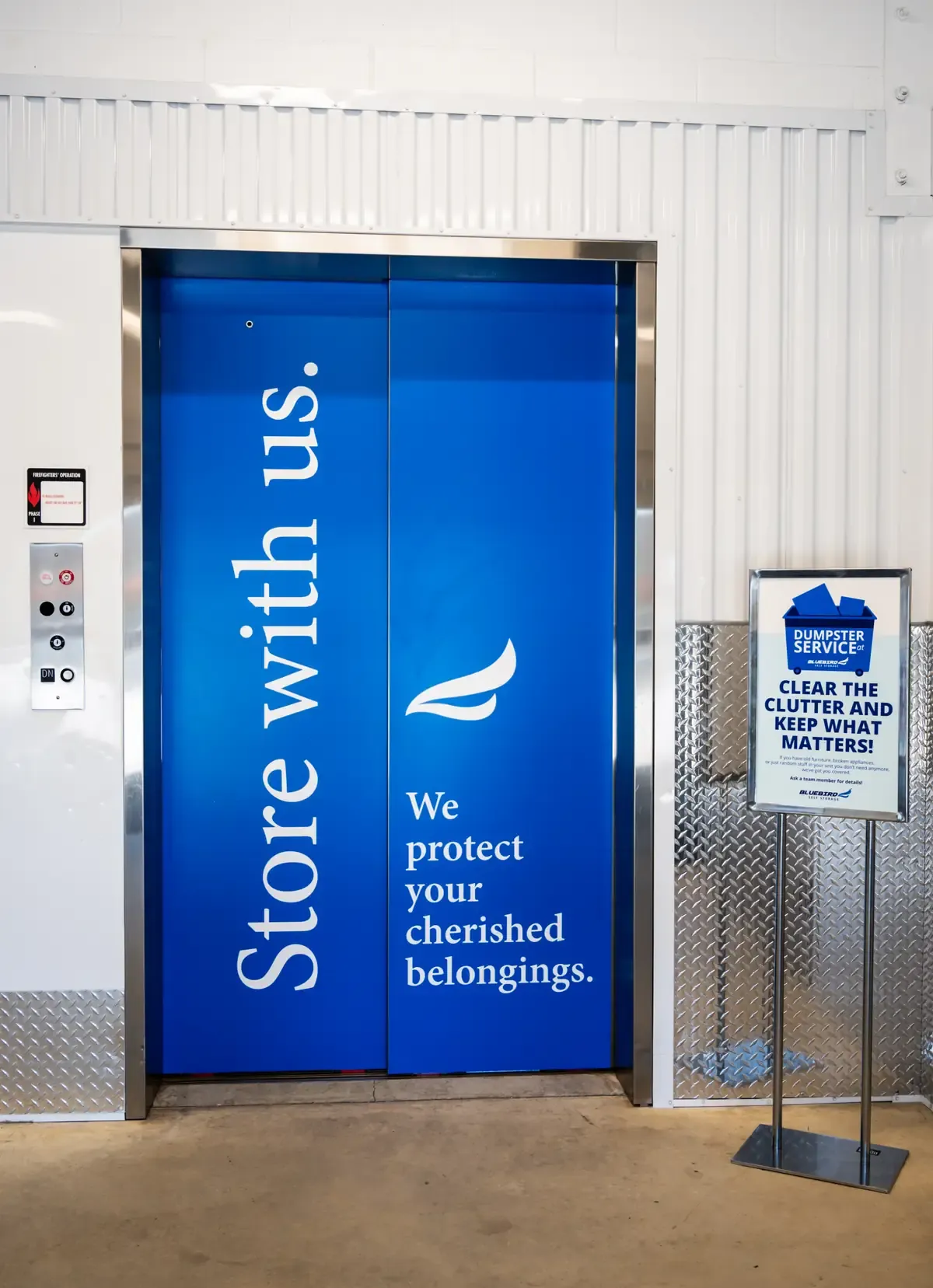 Blue elevator wrap reading "Store with us. We protect your cherished belongings."