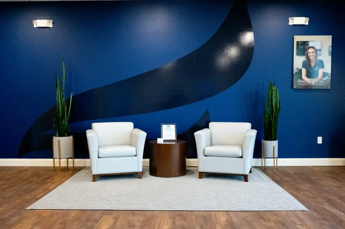 Bluebird Self Storage lobby seating area with white chairs and blue branded accent wall
