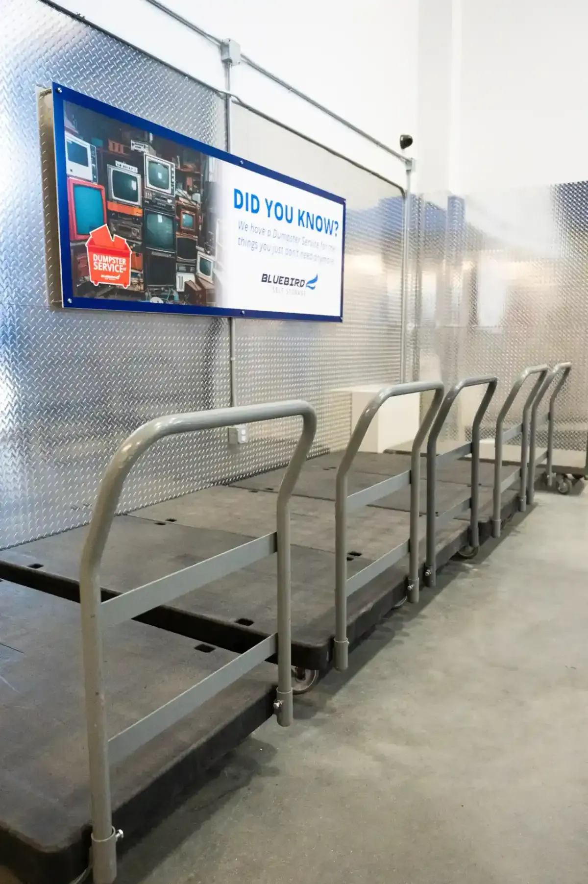 Moving carts lined up near dumpster service sign