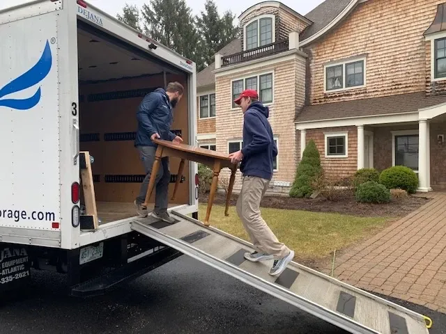 Two Bluebird Self Storage employees loading furniture on to truck.