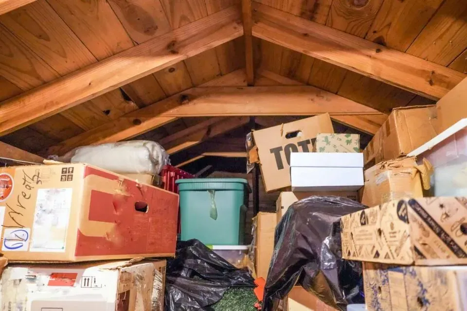A disorganized attic with boxes, bins, and other items.