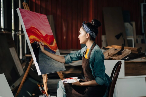 Female artist draws art piece with palette and brush painting at studio.