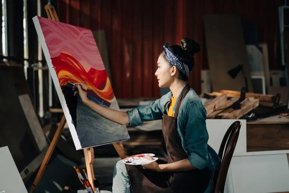 Female artist draws art piece with palette and brush painting at studio.