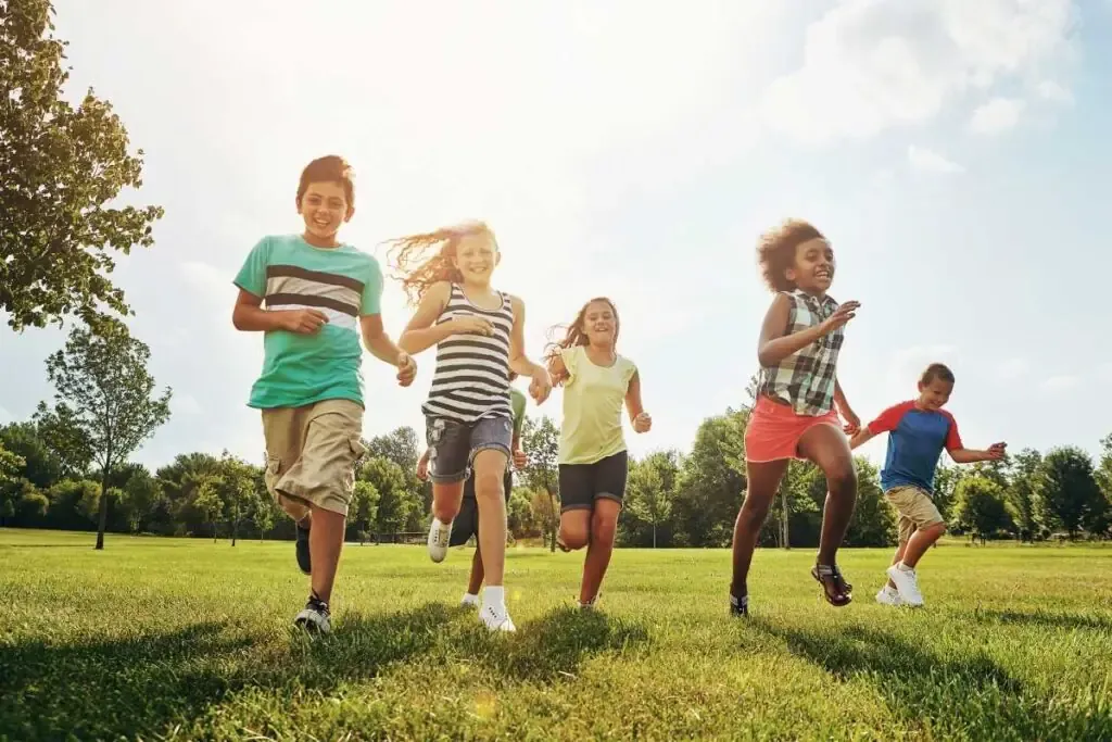 Children running in an open field in a park.