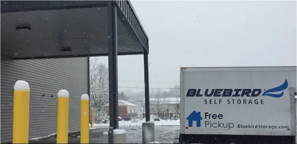 Bluebird Self Storager moving truck parked outside while it snows.